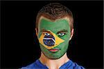 Composite image of serious young brasil fan with facepaint against black