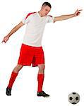 Fit football player playing with ball on white background