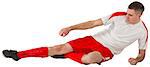 Fit football player playing and kicking on white background