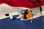 Football player in orange kicking against digitally generated dutch national flag