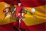 Football player in red kicking against digitally generated spanish national flag