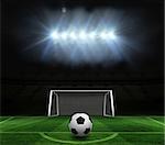 Black and white football against football pitch and goal under spotlights