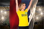 Excited football fan in brasil tshirt holding russia flag against vast football stadium with fans in yellow
