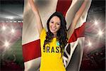 Excited football fan in brasil tshirt holding england flag against vast football stadium with fans in red