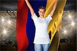 Pretty football fan in white cheering holding colombia flag against vast football stadium with fans in yellow