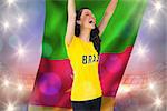 Excited football fan in brasil tshirt holding cameroon flag against large football stadium under purple sky