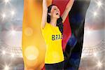 Excited football fan in brasil tshirt holding germany flag against large football stadium under cloudy blue sky