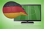 Football in germany colours flying out of tv against green vignette