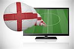 Football in england colours flying out of tv against white background with vignette