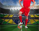Composite image of football player standing with flag ball against large football stadium with brasilian fans