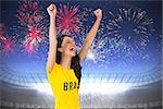 Excited football fan in brasil tshirt against fireworks exploding over football stadium