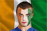 Composite image of serious young football fan in face paint against ivory coast national flag