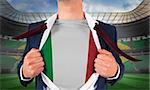 Businessman opening shirt to reveal italy flag against large football stadium with brasilian fans