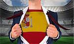 Businessman opening shirt to reveal spain flag against large football stadium under spotlights