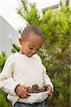 Boy Collecting Pine Cones in Sweater, Maryland, USA