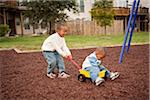 Boy Pulling Brother in Wagon at Playground, Maryland, USA