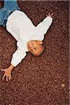 Portrait of Happy Boy Laying in Rubber Mulch at Playground, Maryland, USA