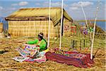 Woman in Peruvian clothing displaying traditional art outdoors, Floating Island of Uros, Lake Titicaca, Peru