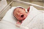 Newborn Baby Girl Yawning in Hospital Bassinet