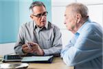 Senior, male doctor conferring with senior, male patient in office, discussing medication, Germany