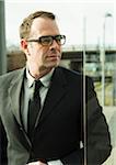 Portrait of businessman wearing glasses, standing at train station outdoors, Mannheim, Germany