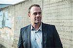 Portrait of businessman standing next to stone wall outdoors, Germany