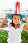 Portrait of young girl outdoors, wearing American, patriotic construction paper hat, Independence Day, USA