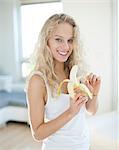 Portrait of young woman peeling banana in house
