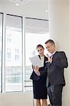 Businessman using digital tablet with female colleague in office