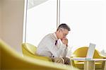 Side view of serious businessman looking at laptop in lobby