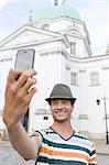 Young man taking self portrait outside St. Casimir Church, Warsaw, Poland