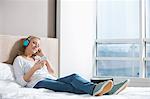 Full length of relaxed woman listening music in bedroom