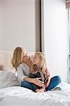 Happy woman and daughter looking at each other in bedroom