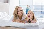 Portrait of happy mother and daughter lying in bed