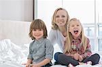 Portrait of happy mother with children in bedroom