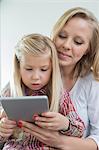 Loving woman with daughter using digital tablet at home