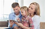 Parents with daughter using digital tablet at home