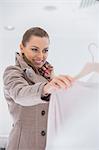 Happy young woman choosing sweater in store