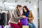 Young woman with friend looking into shopping bag at store