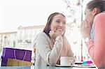 Happy female friends gossiping at outdoor cafe