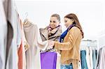 Young female friends choosing sweater in store