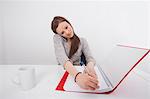 Businesswoman writing notes while answering smart phone in office