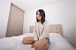 Portrait of beautiful young woman in sweater on bed