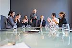 Business people applauding colleague in meeting