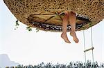 Woman's feet dangling out of nest tree house