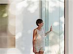 Pensive woman standing at sunny window