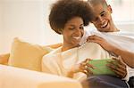 Couple using digital tablet on sofa