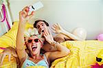 Couple taking self-portraits with camera phone in bed after party