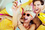 Couple taking self-portraits in bed at party