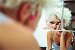 Hungover woman examining herself in mirror